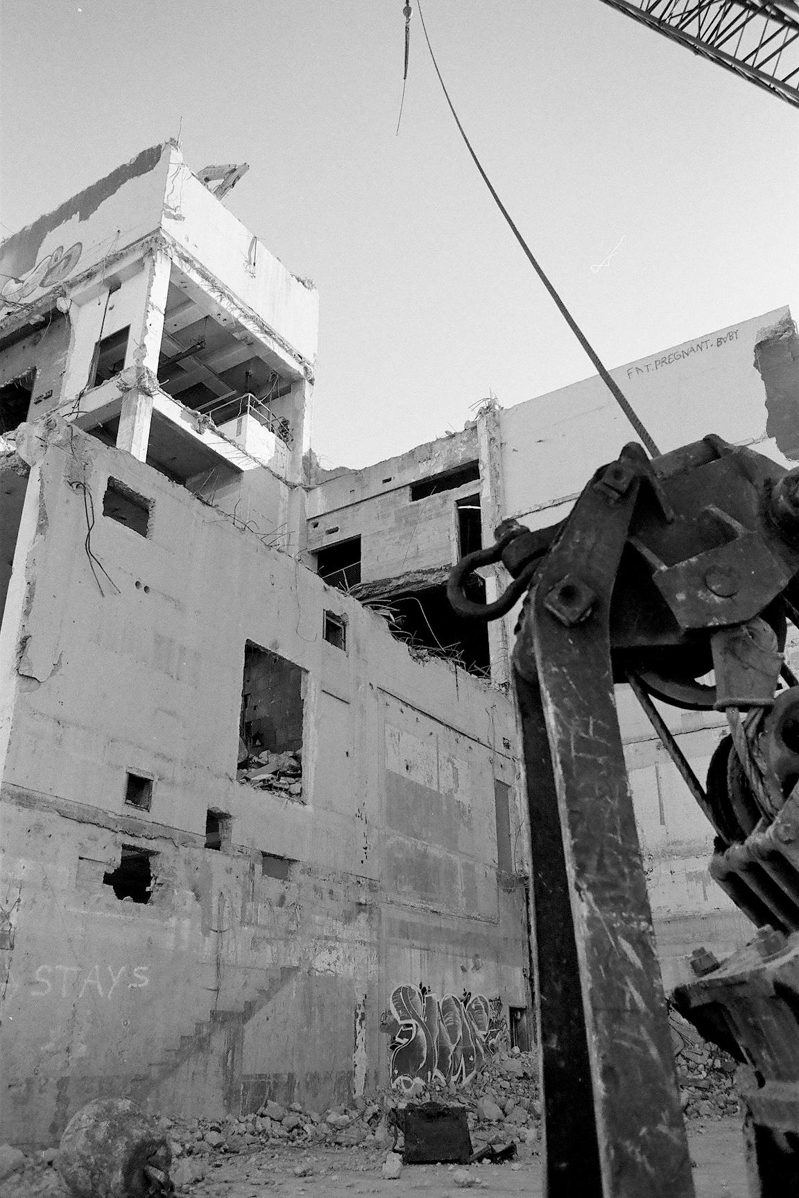 A black-and-white photo of a building in the process of being torn down.